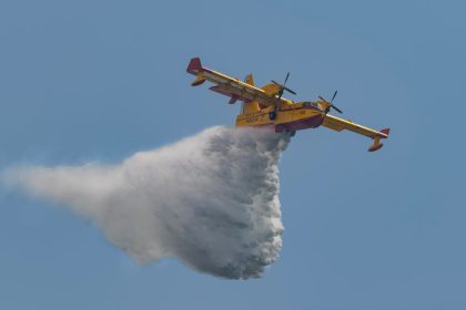 Avião de combate a incêndios despeja água sobre uma área em chamas durante uma operação de emergência.