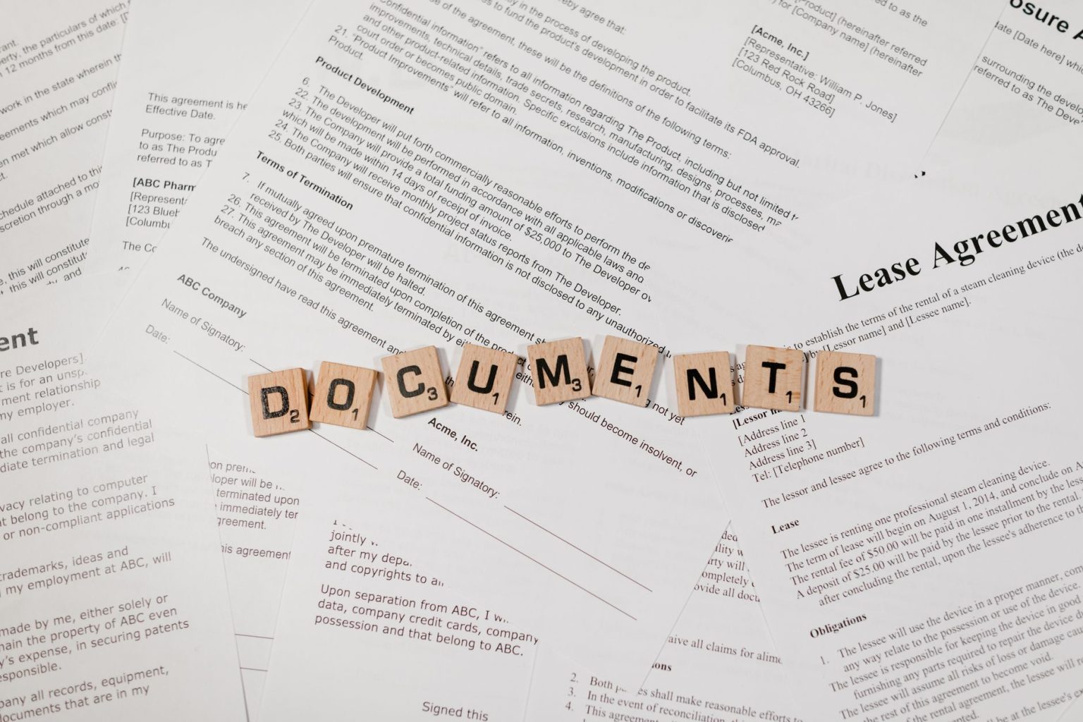 Peças de jogo formam a palavra “DOCUMENTS” sobre documentos e contratos dispostos em uma mesa.