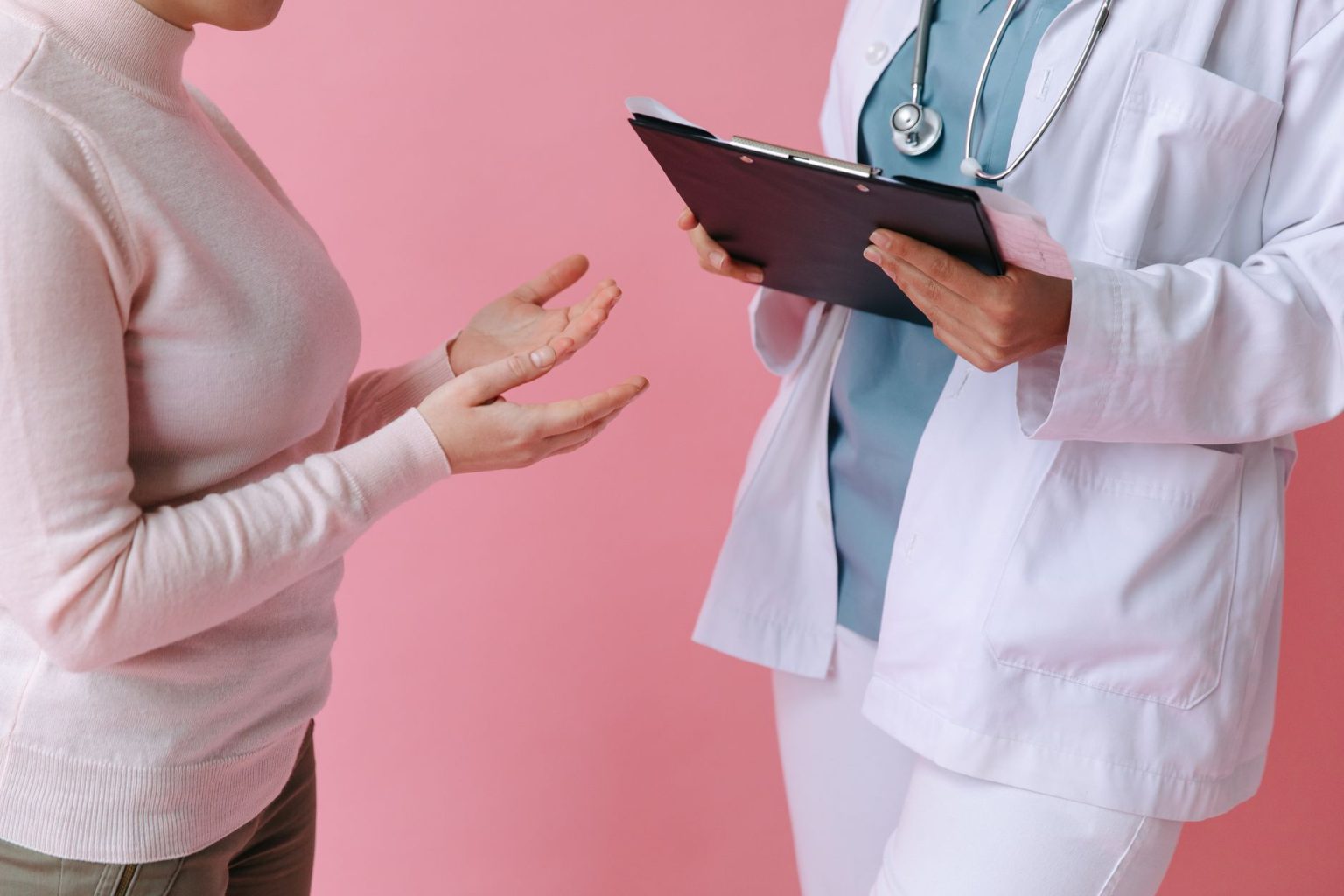 Paciente conversa com profissional de saúde durante consulta médica, em ambiente clínico.